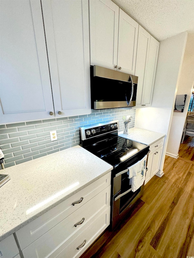 Kitchen with white cabinetry, light stone countert