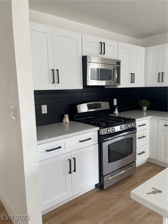 Kitchen featuring white cabinets, light wood-style