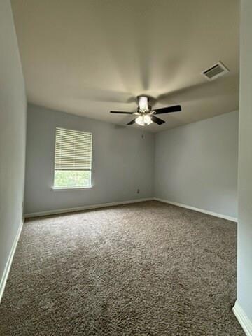 Carpeted empty room with baseboards, a ceiling fa