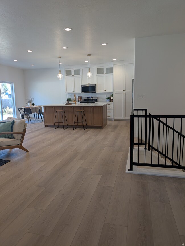 Kitchen with light countertops, white cabinets, open floor plan, pendant lighting, and brown cabinetry
