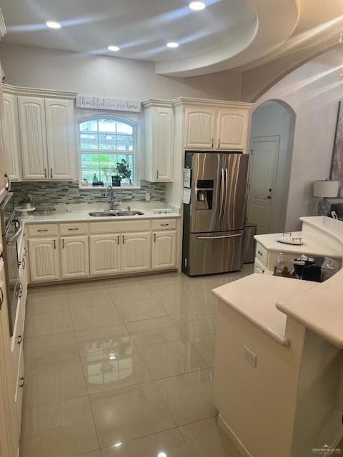 Kitchen featuring light tile floors, sink, tasteful backsplash, and fridge
