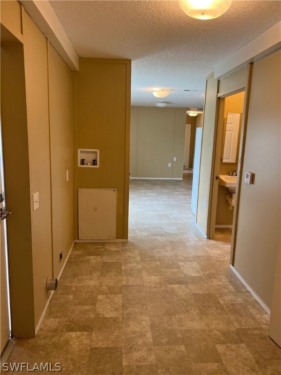 Hall featuring tile flooring and a textured ceiling