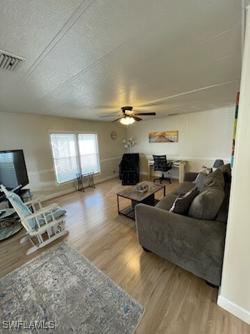 Living room with ceiling fan, wood-type flooring,