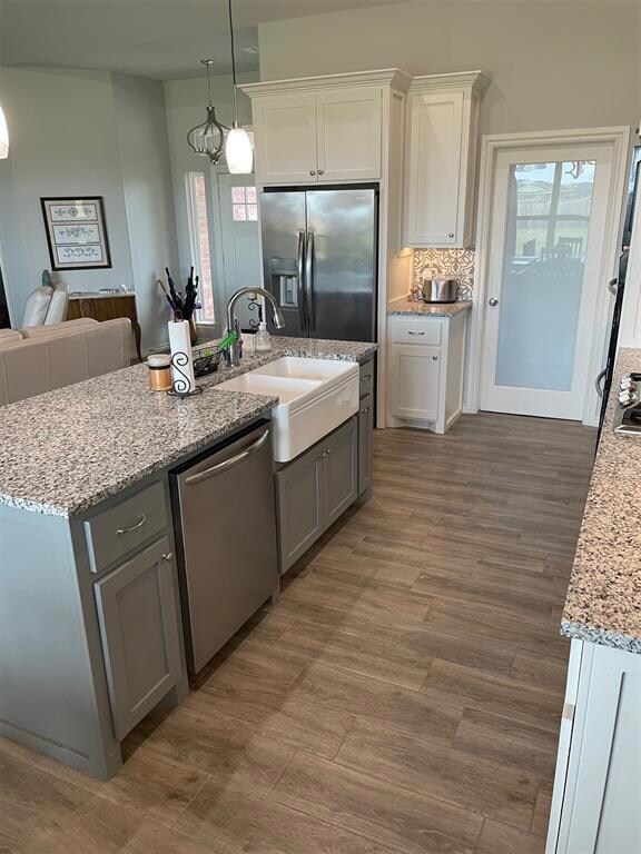 Kitchen with dishwasher, white cabinetry, light st