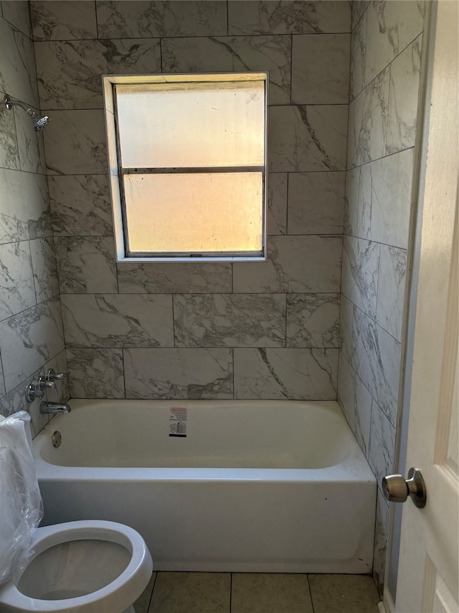 Bathroom with washtub / shower combination and tile patterned flooring