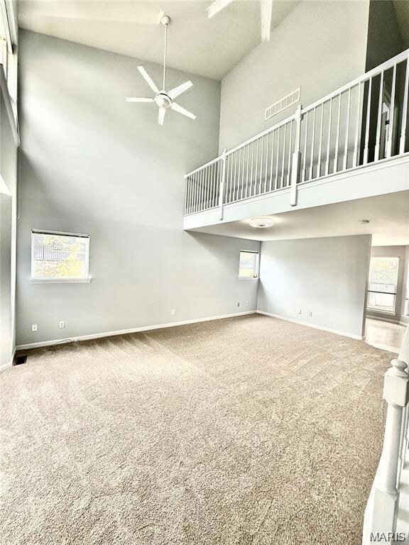 Unfurnished living room featuring high vaulted ceiling, light carpet, and ceiling fan
