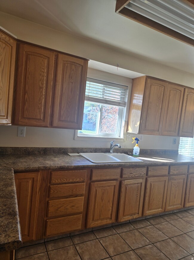 Kitchen featuring brown cabinets, dark countertops, and dark tile patterned flooring