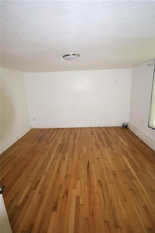 Unfurnished room featuring light wood-type flooring and a textured ceiling