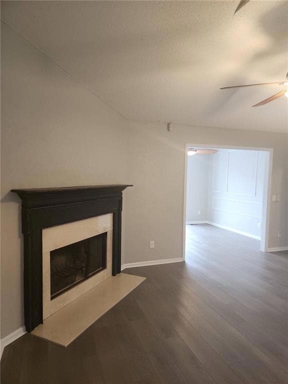 Unfurnished living room with a glass covered fireplace, dark wood-style floors, and a textured ceiling