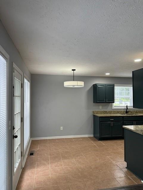 Kitchen with a textured ceiling, baseboards, visib