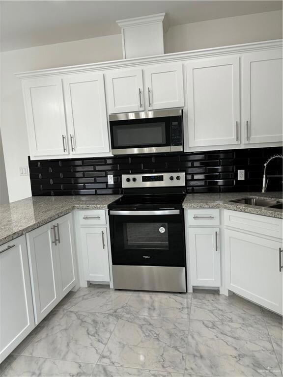 Kitchen with electric range, sink, and white cabinetry