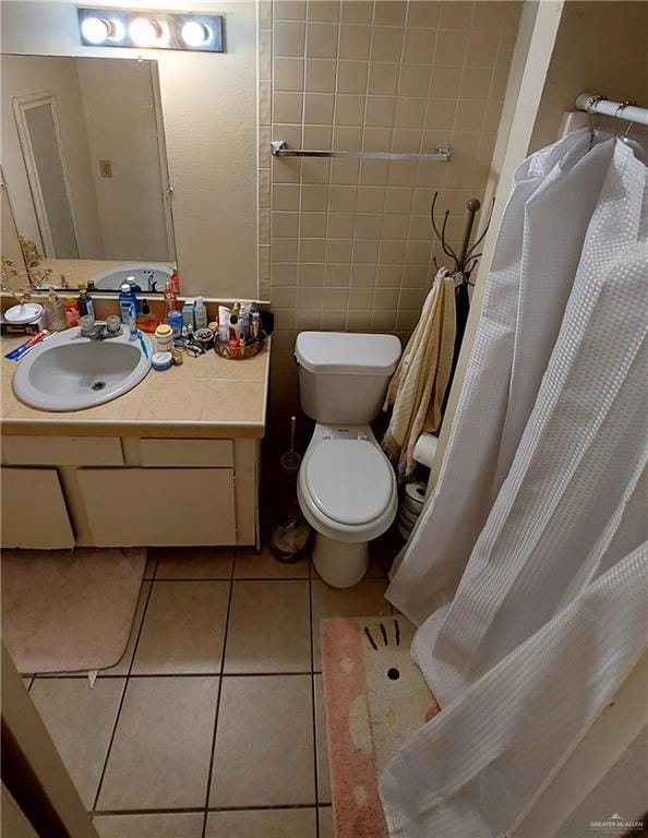 Bathroom featuring light tile patterned floors, vanity, tile walls, and curtained shower