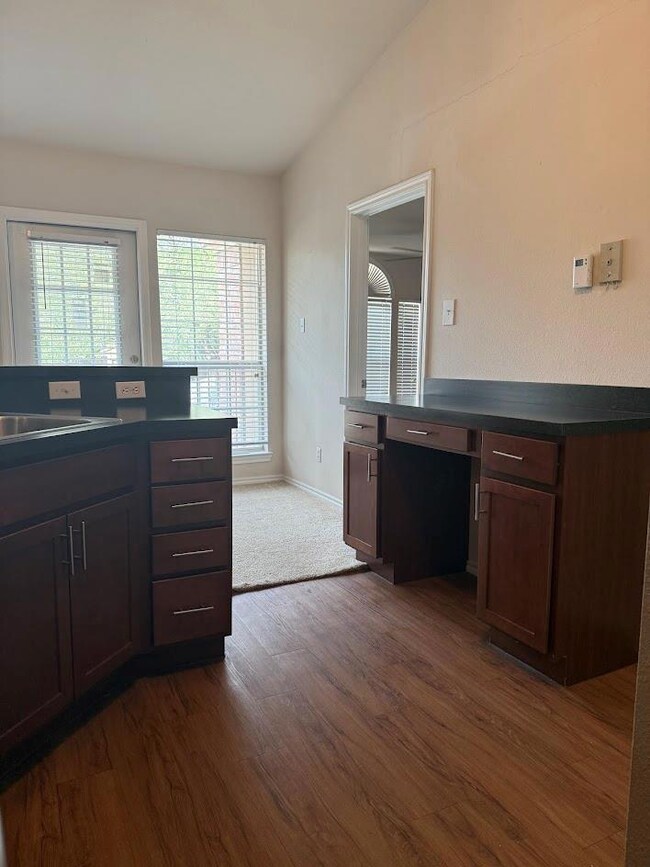 Kitchen featuring vaulted ceiling, dark wood fini