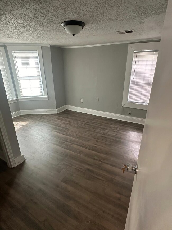 Empty room with a textured ceiling and dark hardwood / wood-style floors