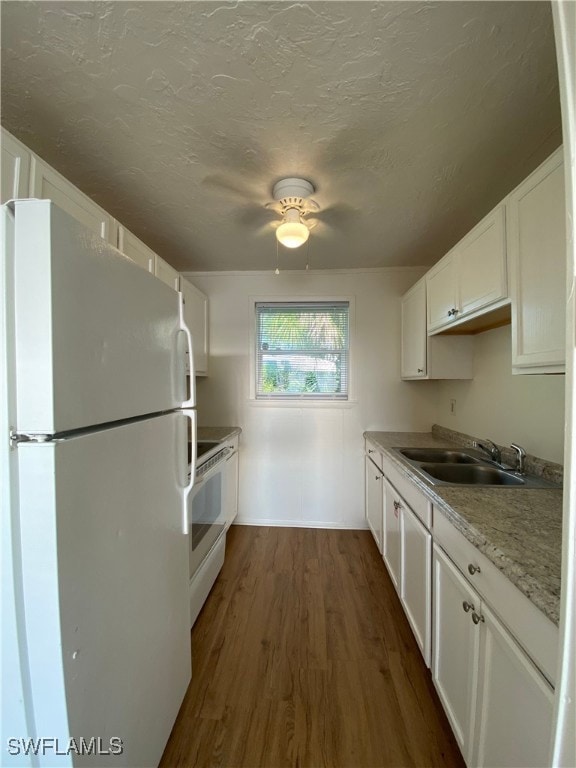 Kitchen featuring white appliances, a sink, dark w