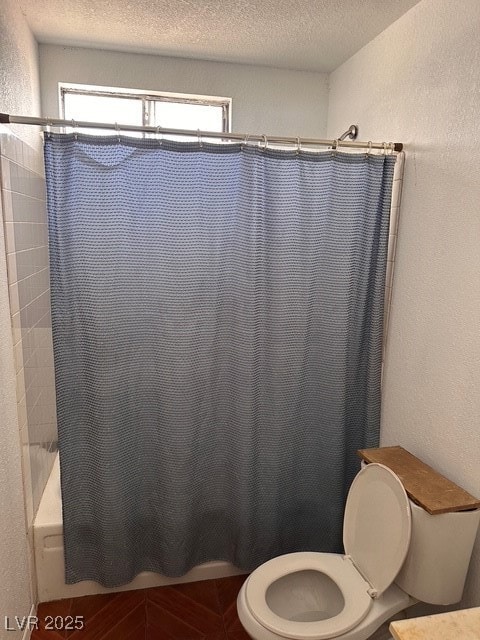 Bathroom with toilet, a textured ceiling, a textur