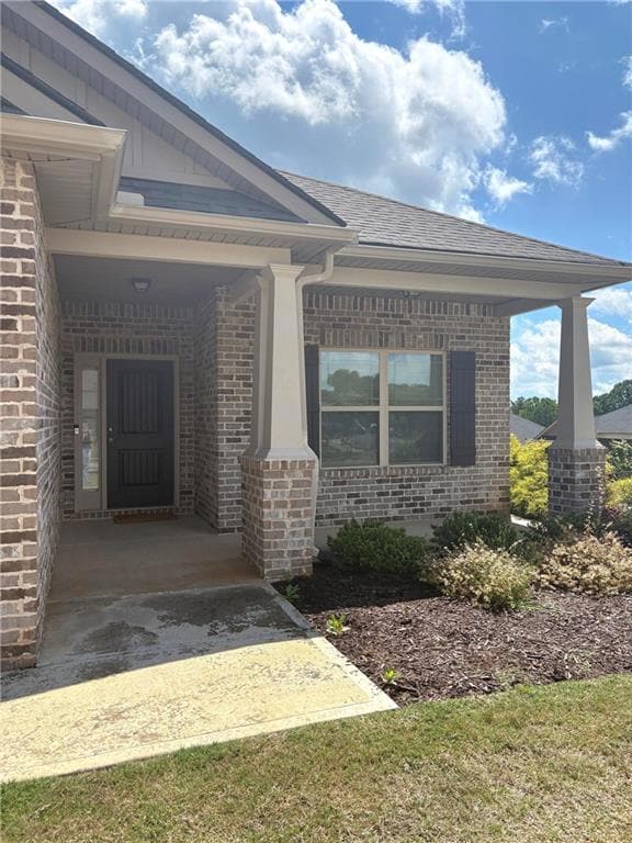 View of exterior entry with brick siding, covered 