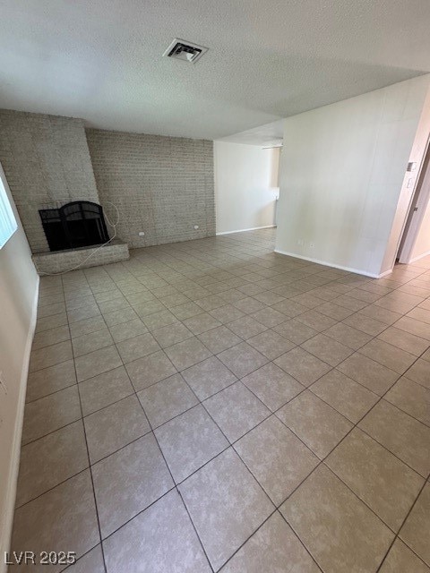 Unfurnished living room with a textured ceiling, a brick fireplace, and tile patterned floors
