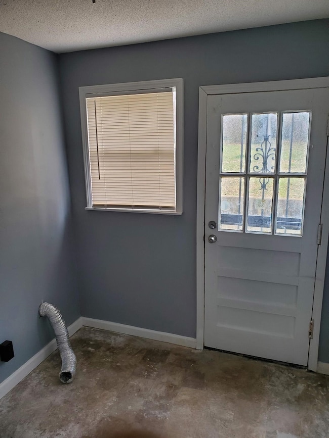Doorway with a textured ceiling, unfinished concre