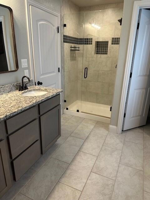 Bathroom with tile flooring, walk in shower, and vanity