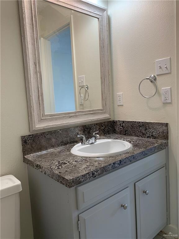 Half bath with a textured wall and vanity