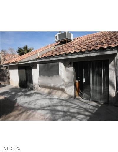 Back of house featuring a tile roof and stucco siding