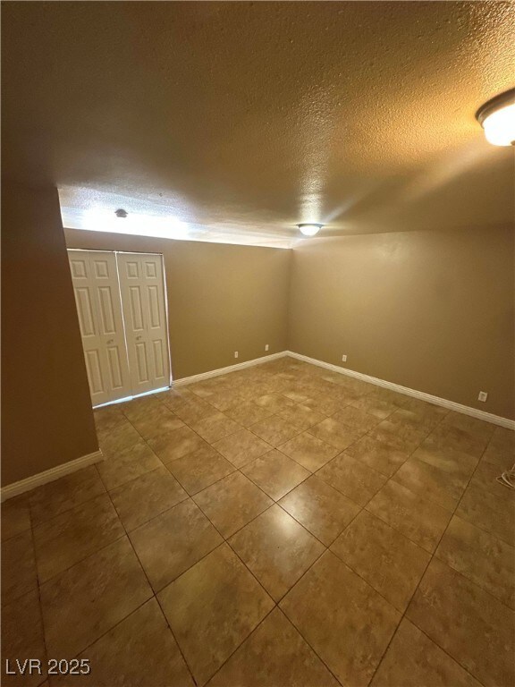 Tiled empty room featuring a textured ceiling and