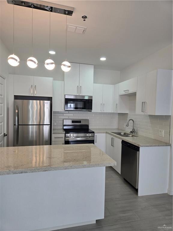 Kitchen featuring stove, refrigerator, a sink, white cabinets, and dishwashing machine