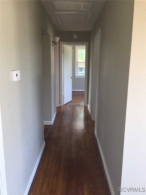 Corridor featuring attic access, dark wood-type fl
