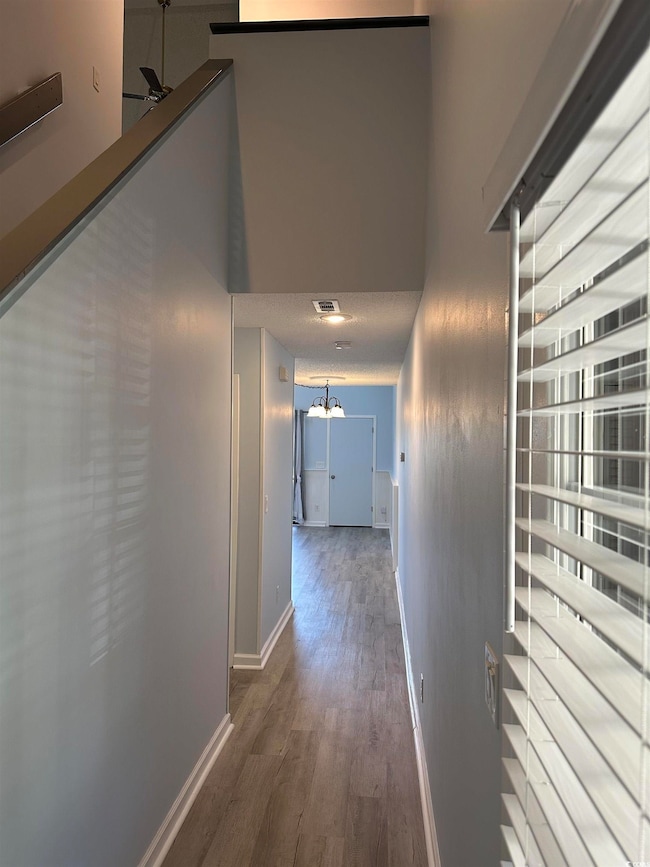 Hallway featuring wood finished floors and a towering ceiling