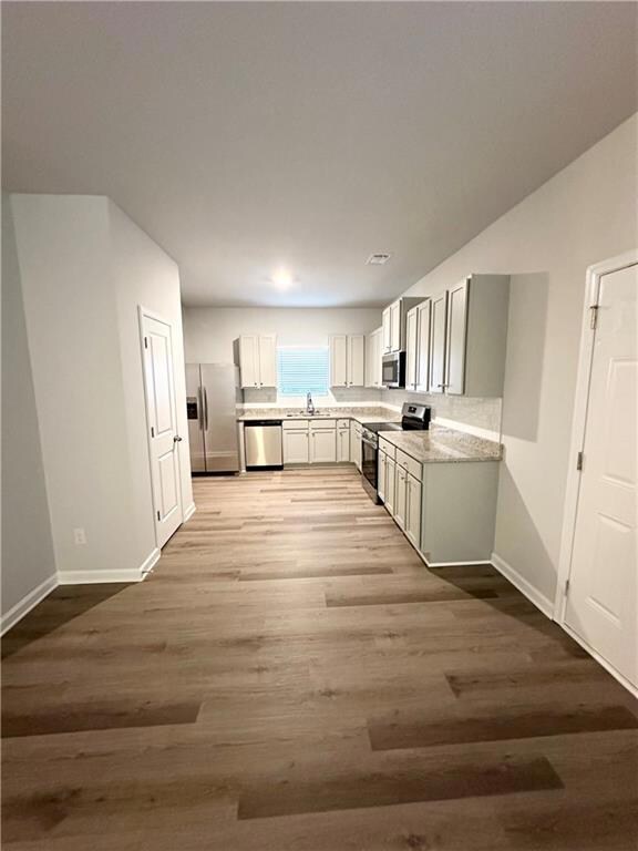 Kitchen featuring appliances with stainless steel finishes, gray cabinetry, decorative backsplash, sink, and light hardwood / wood-style flooring