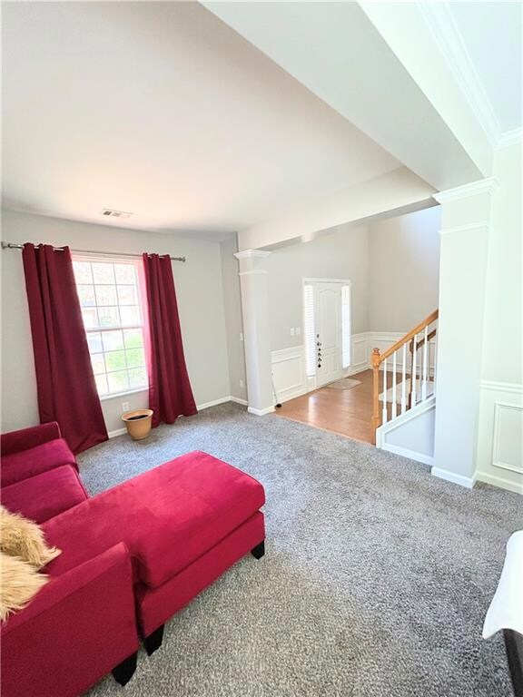 Sitting room with carpet flooring, decorative columns, stairs, a wainscoted wall, and a decorative wall