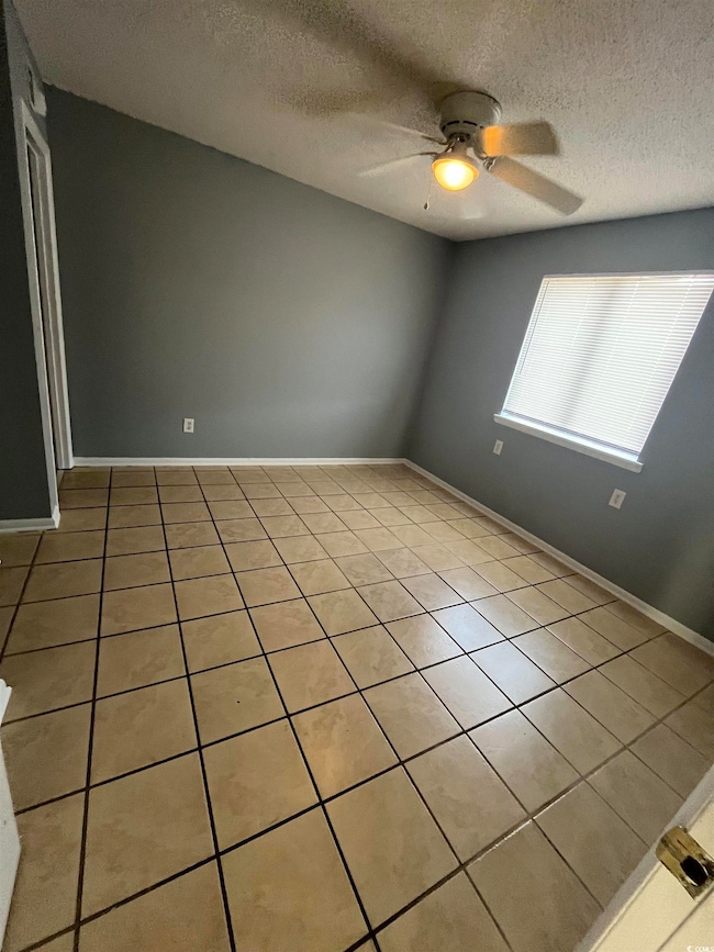 Tiled empty room with ceiling fan and a textured c