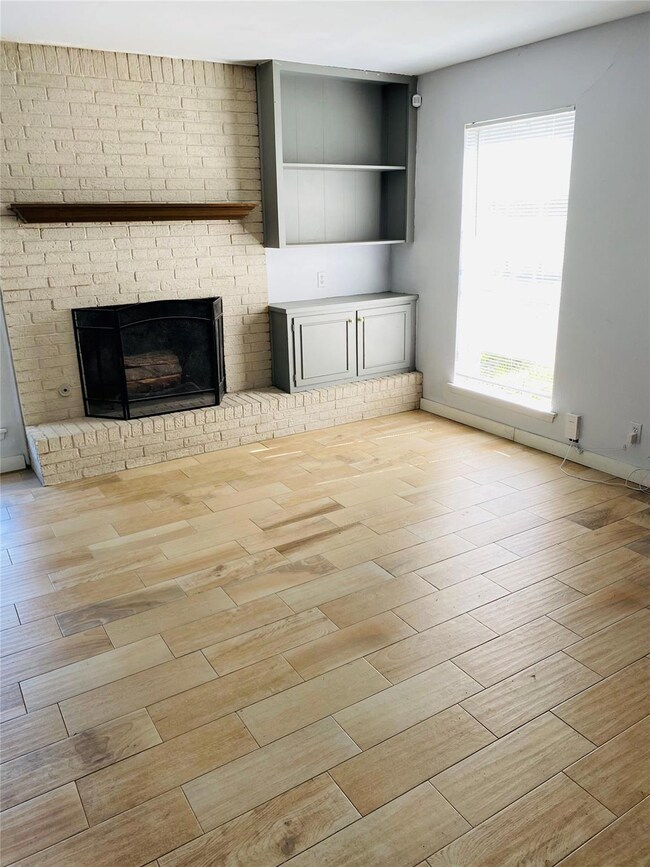 Unfurnished living room featuring a fireplace, ba