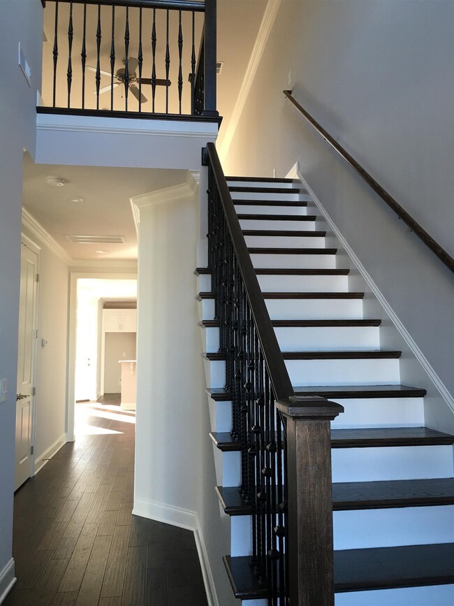 Two story entry with hardwood floors, hardwood stairs, and iron spindles.
