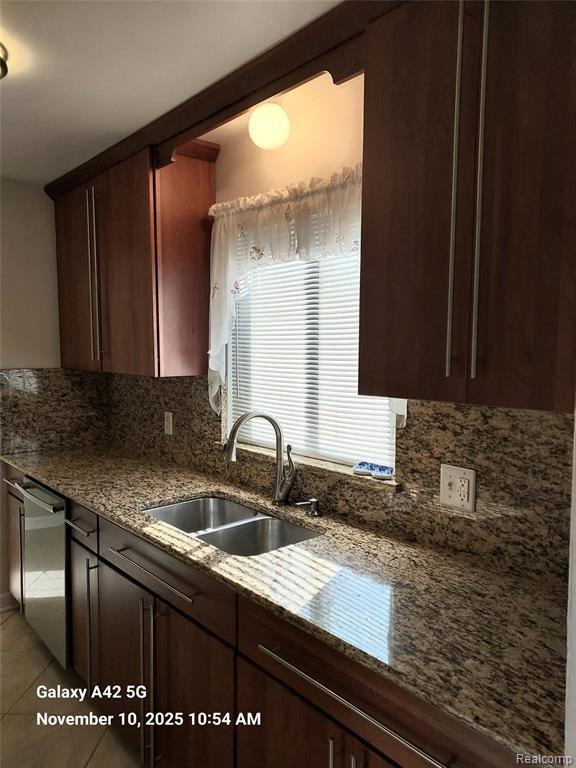 Kitchen with dark brown cabinets, dark stone countertops, decorative backsplash, dishwasher, and light tile patterned flooring