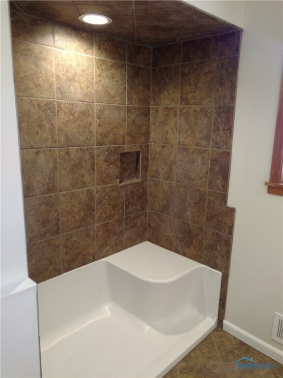 Full size shower with custom tile and a seat.