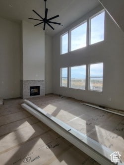 Unfurnished living room with a glass covered fireplace, a high ceiling, and ceiling fan