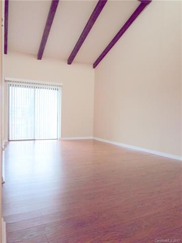 Den with vaulted ceiling & wood laminate floors.