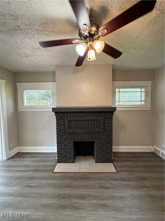 Detailed view of a textured ceiling, a brick fireplace, wood finished floors, and ceiling fan