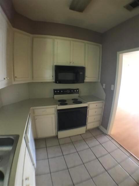 Kitchen with white cabinets, visible vents, white
