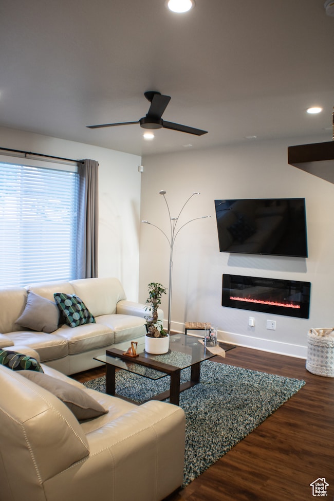 Living room with a glass covered fireplace, wood finished floors, recessed lighting, and ceiling fan
