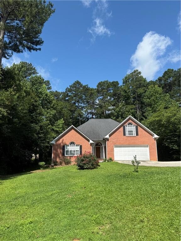 Single story home featuring a garage, a front yard, brick siding, and driveway