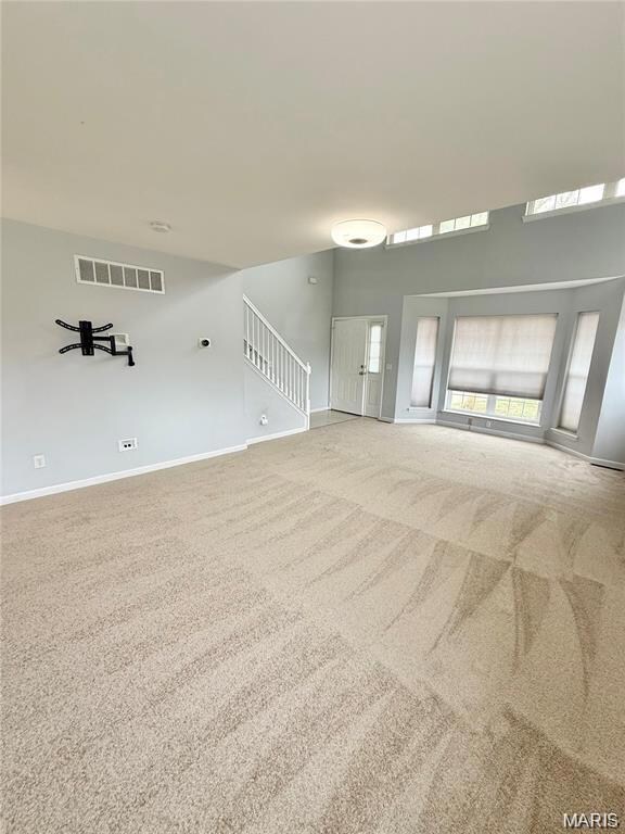 Unfurnished living room with carpet and stairway