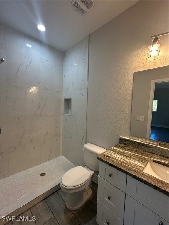 Bathroom featuring toilet, a tile shower, and vani