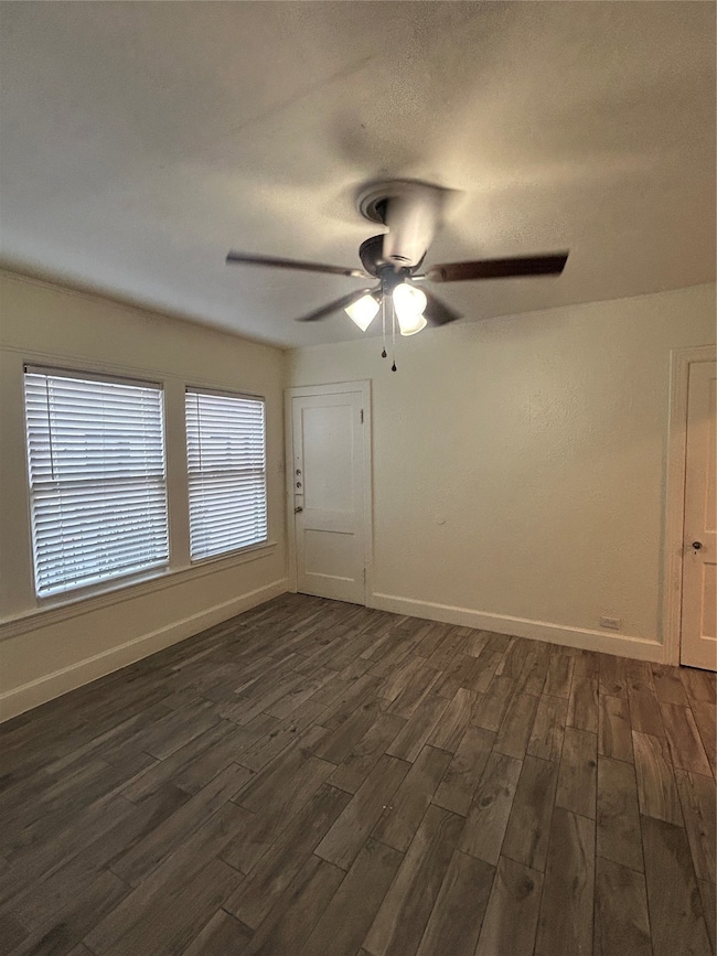Empty room with dark wood-style floors, a textured ceiling, and ceiling fan
