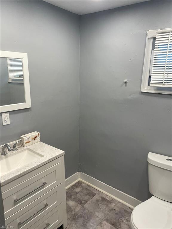 Bathroom with dark tile flooring, vanity with extensive cabinet space, and mirror