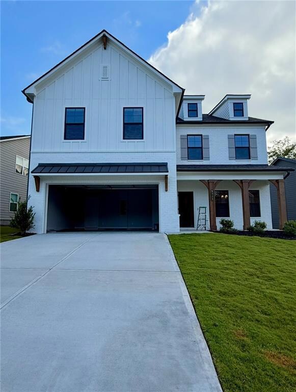 Modern farmhouse featuring driveway, a front yard, an attached garage, a metal roof, and a standing seam roof