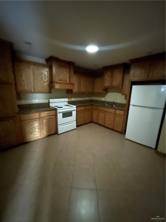 Kitchen featuring light tile floors, range, refrigerator, and sink