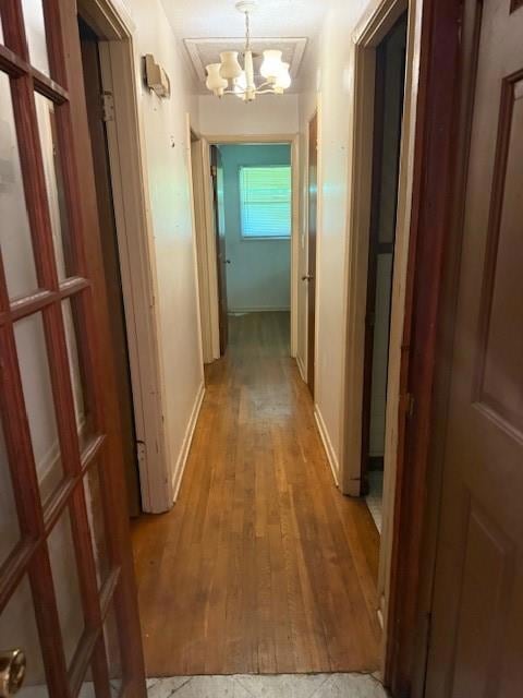 Corridor with a chandelier, light wood-type flooring, and baseboards